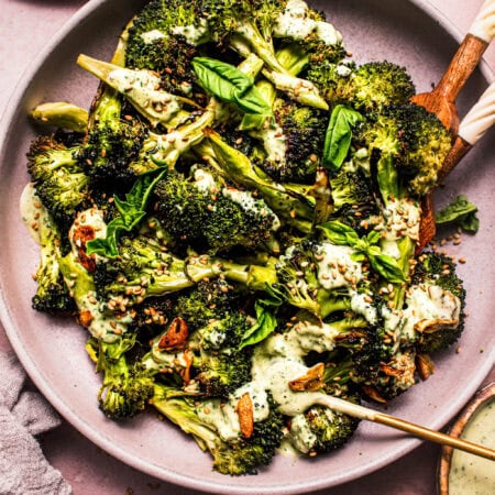 Overhead shot of bowl of broccoli drizzled with basil tahini dressing.