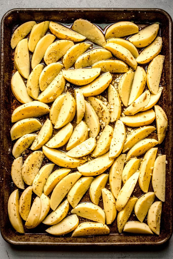 Sliced potatoes on baking sheet before roasting.