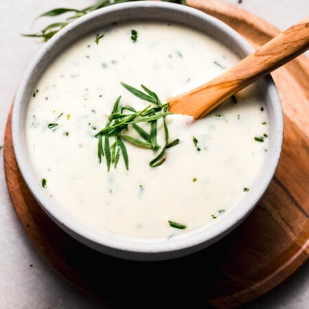 Side view of tarragon cream sauce in bowl topped with tarragon sprig.