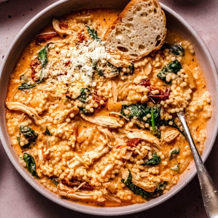 Overhead close up of bowl of marry me chicken soup next to glass of wine.
