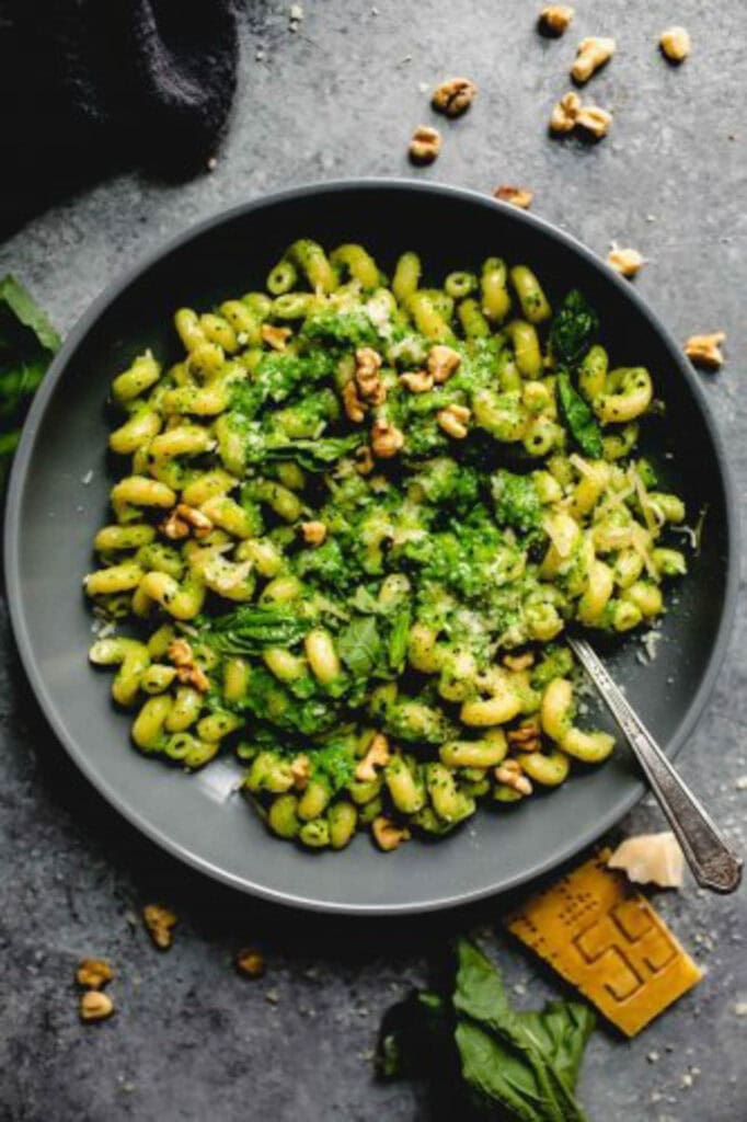Overhead shot of broccoli pesto pasta in grey bowl with spoon.