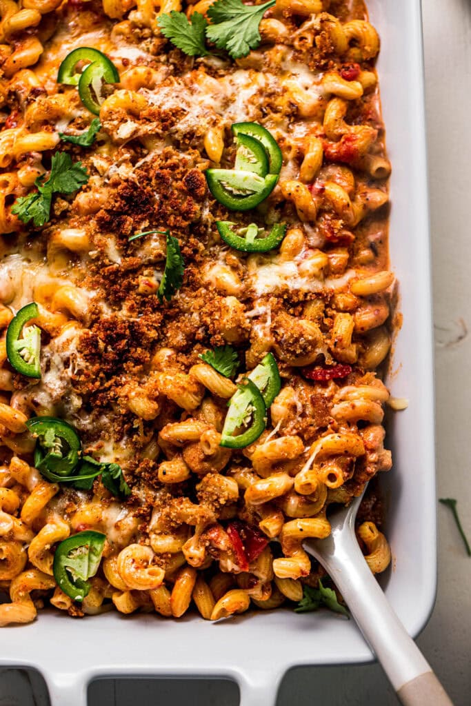 Chorizo macaroni and cheese in baking dish with serving spoon.