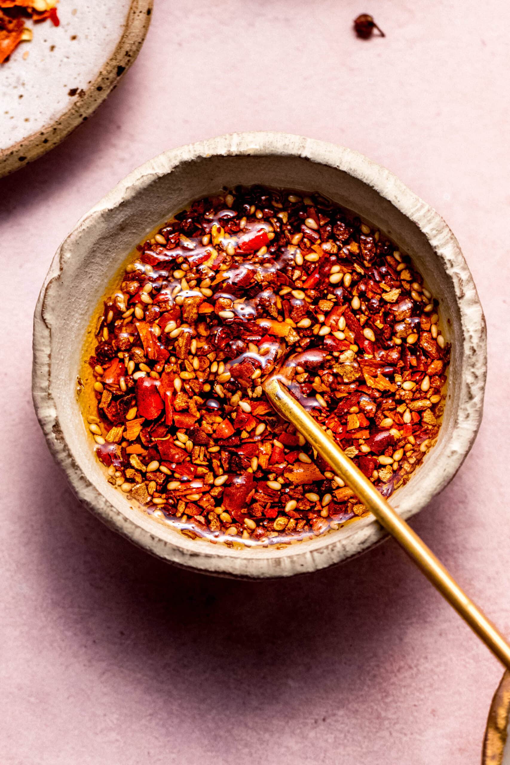 Bowl of chili crisp on pink countertop.