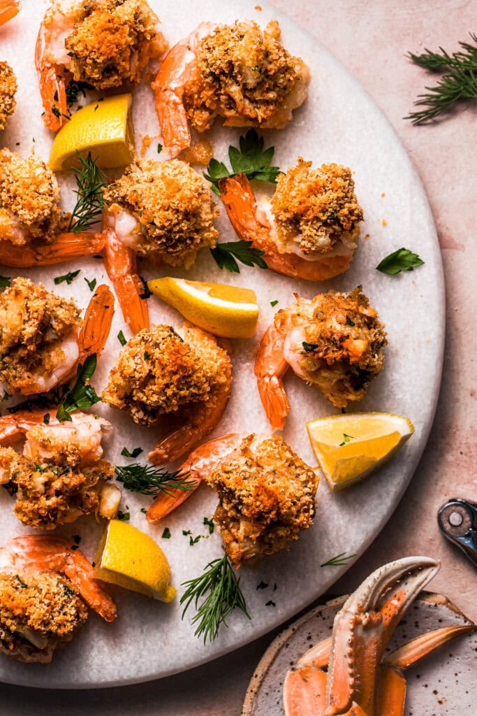 Shrimp stuffed with crabmeat on serving platter with lemon wedges.