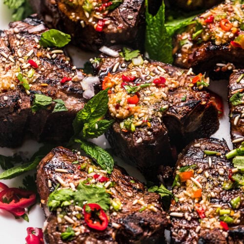 Grilled lamb chops on serving plate with crying tiger sauce.