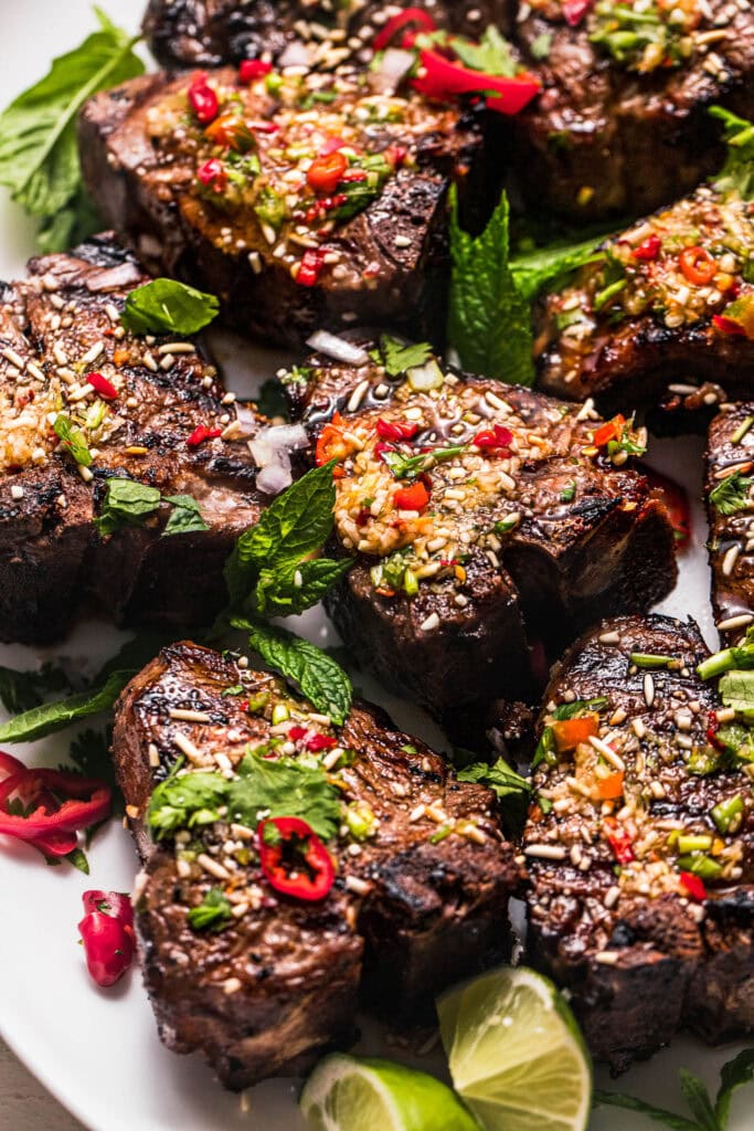 Grilled lamb chops on serving plate with crying tiger sauce.