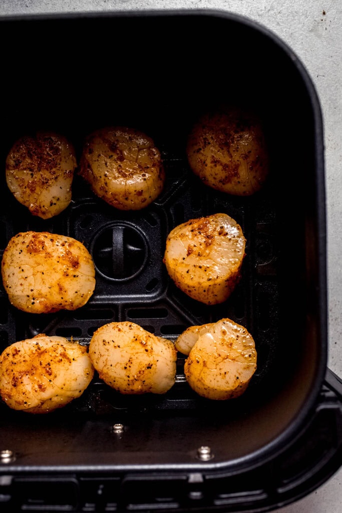 Raw scallops in air fryer basket.
