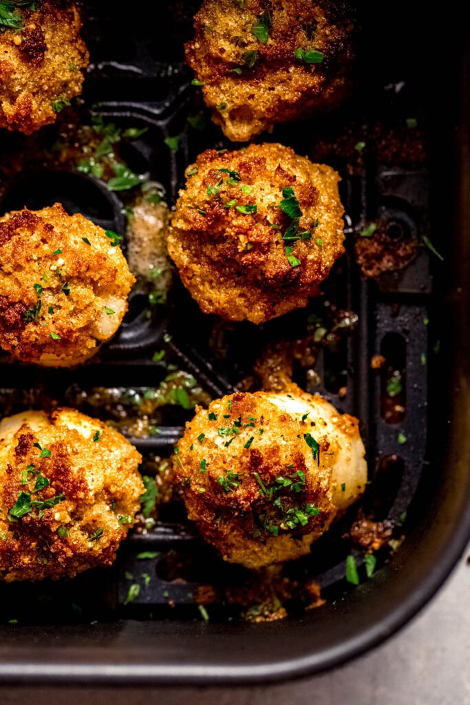 Cooked panko topped scallops in air fryer basket.