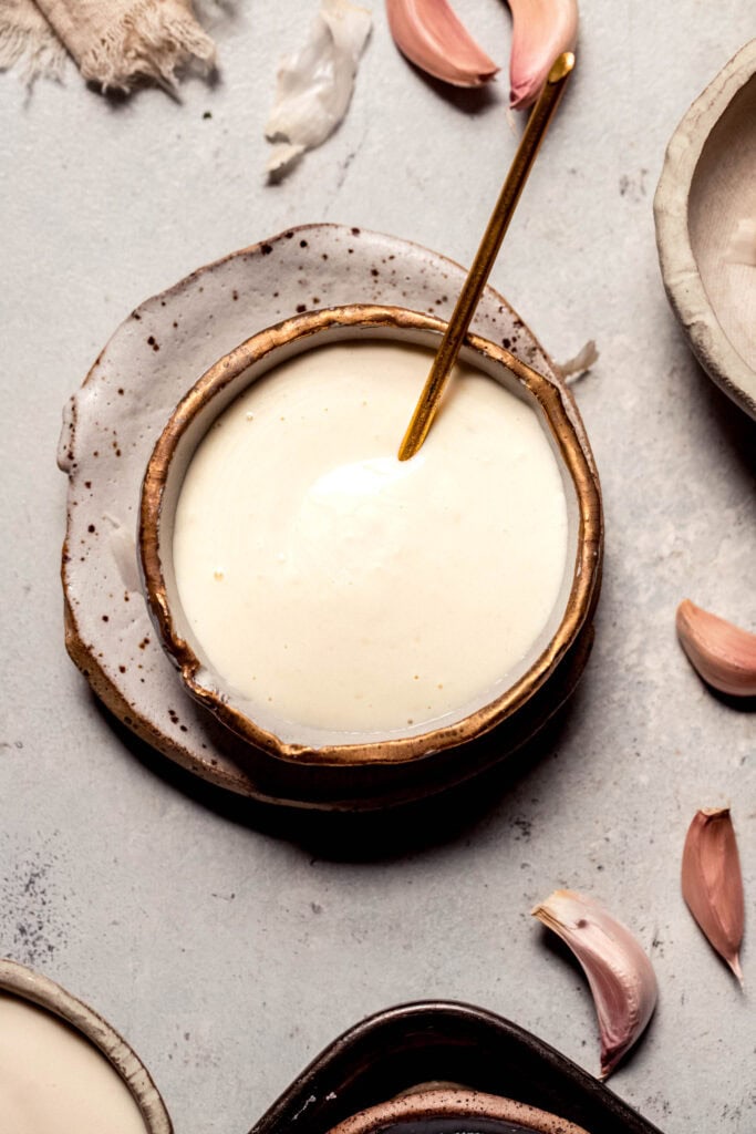 Overhead shot of creamy garlic aioli in small bowl with spoon.