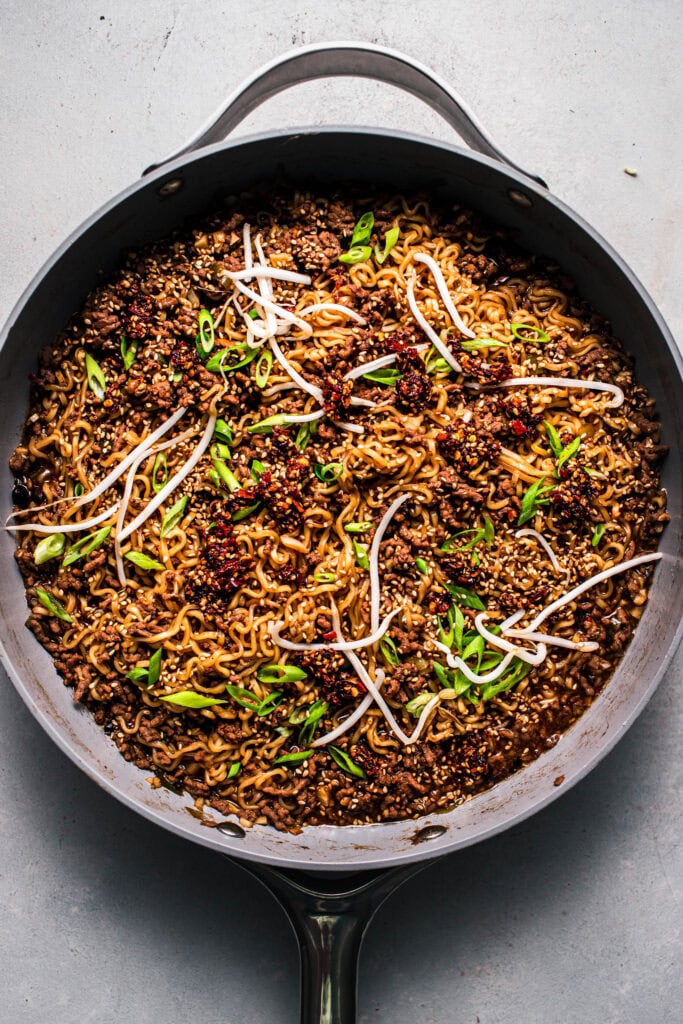 Finished ground beef ramen in skillet topped with bean sprouts.