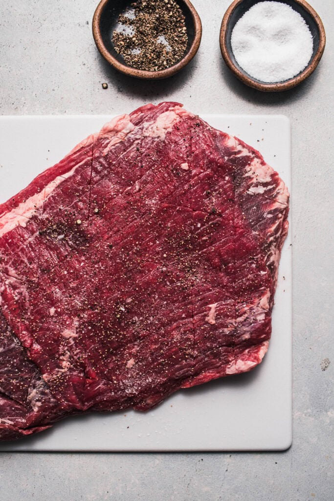 Flank steak seasoned with salt and pepper.