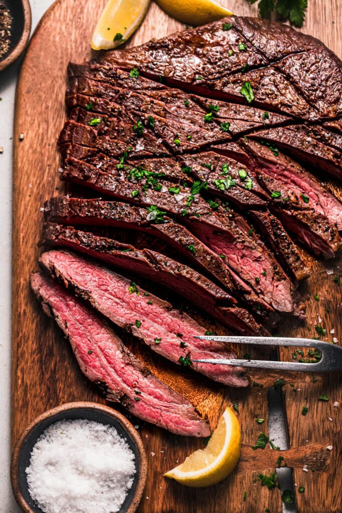 Close up of sliced flank steak on cutting board.