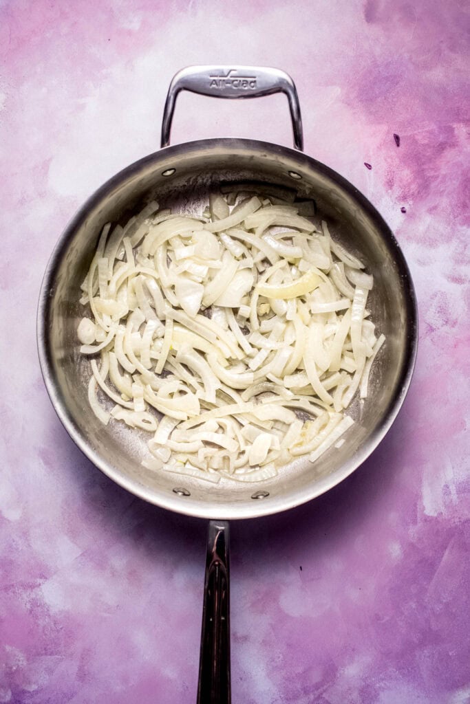 Onions being sauteed in skillet.