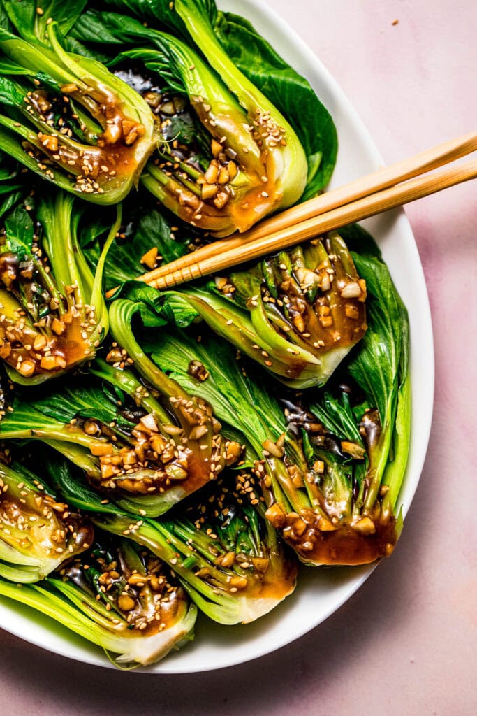 Plate of tender bok choy topped with savory garlic sauce and toasted sesame seeds.