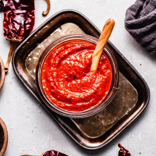 Overhead shot of finished Guajillo sauce in glass bowl with wooden spoon.