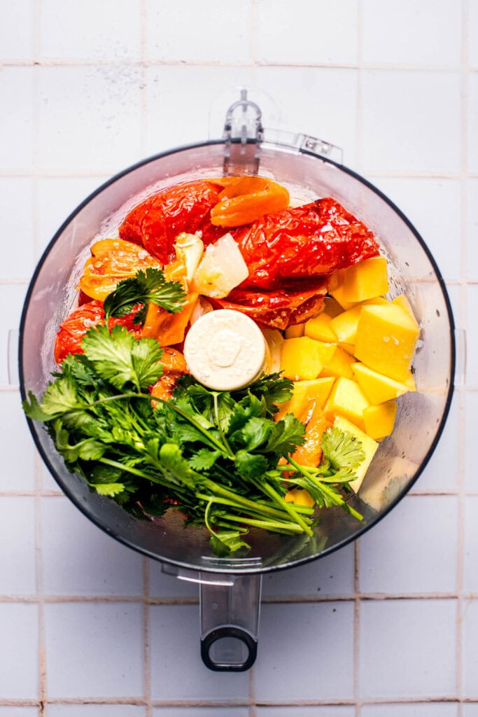 Ingredients for mango habanero salsa in food processor bowl before processing.