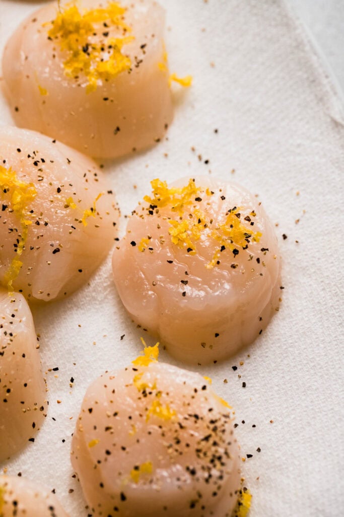 Scallops sprinkled with pepper and lemon zest.