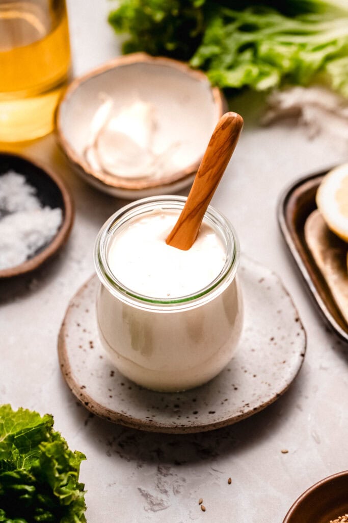 spoon dipping into jar of tahini dressing.