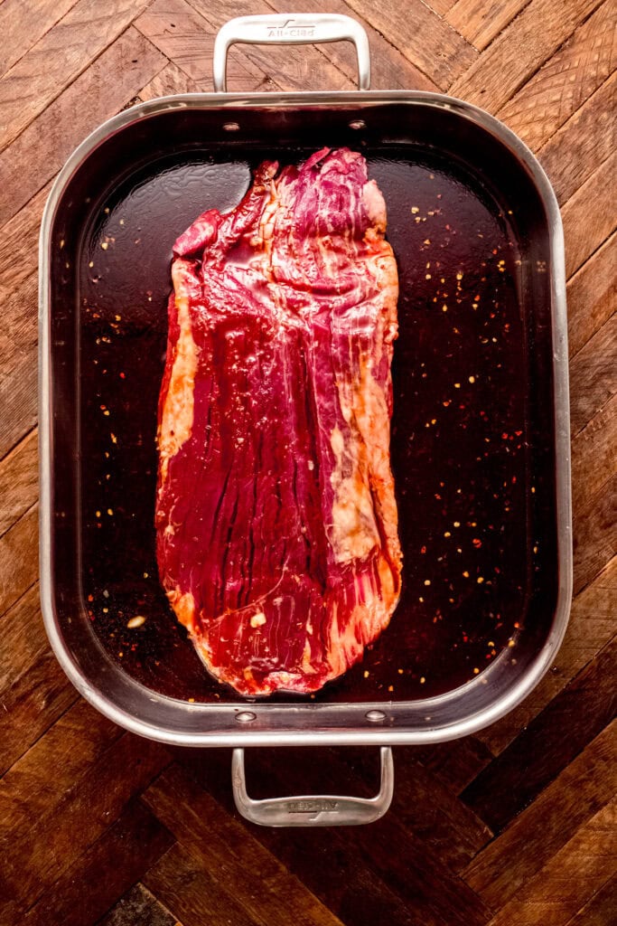 Flank steak marinating in pan.