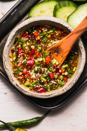 Overhead close up of crying tiger sauce in bowl with wooden spoon.