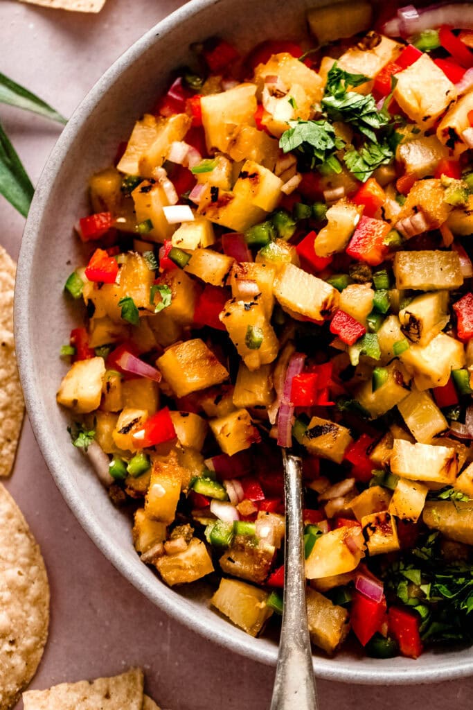 Overhead close up of grilled pineapple salsa in bowl with spoon.