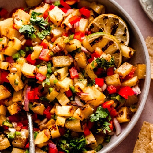 Side view of finished grilled pineapple salsa in bowl with serving spoon.