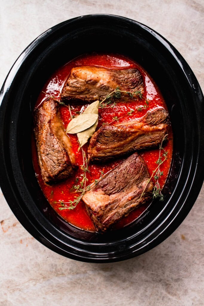 Browned short ribs added to slow cooker.