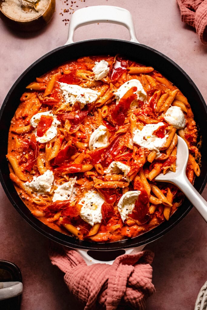 Spicy vodka rigatoni in skillet with serving spoon.