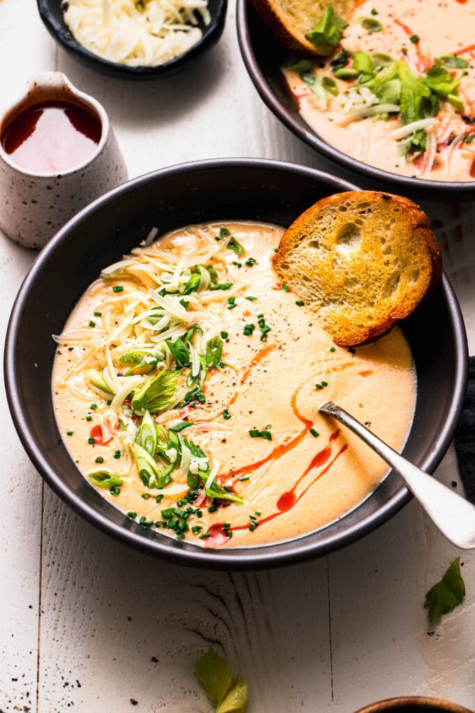 Side view of buffalo cauliflower soup in bowl topped with green onions.