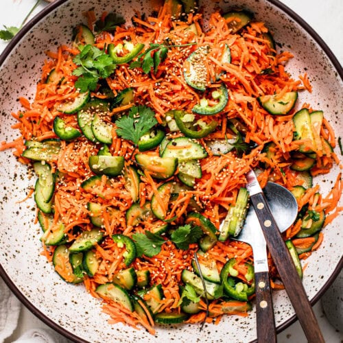 Prepared asian style carrot cucumber salad in large speckled serving bowl.