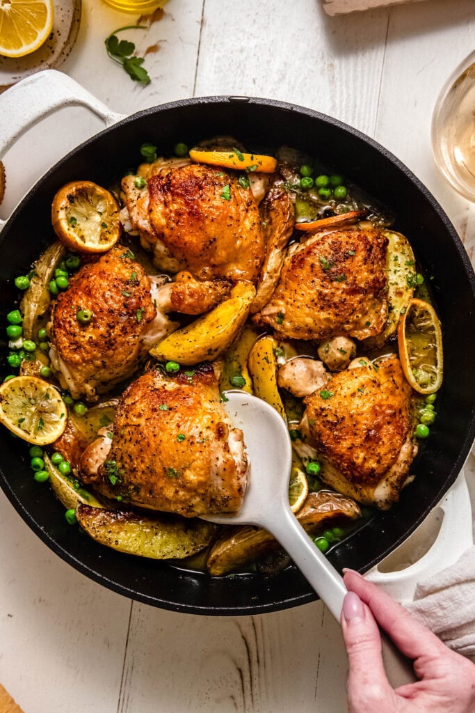 Overhead shot of finished chicken vesuvio in skillet with serving spoon.