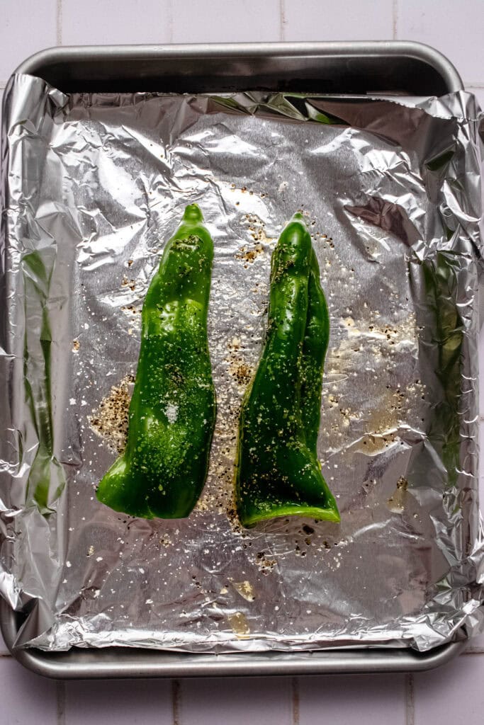 Poblano peppers roasting on baking sheet.
