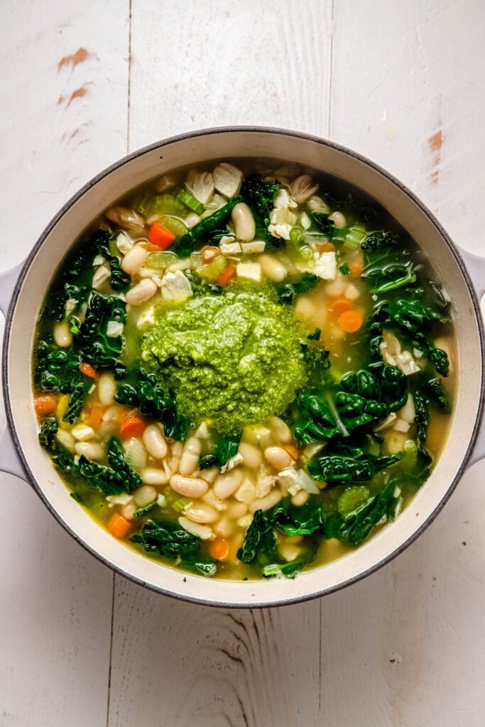 Pesto dolloped on pot of chicken soup.