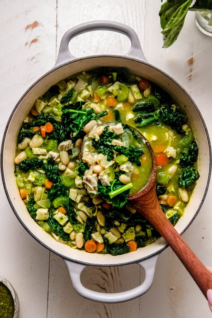 Finished pesto chicken soup in pot with ladle.