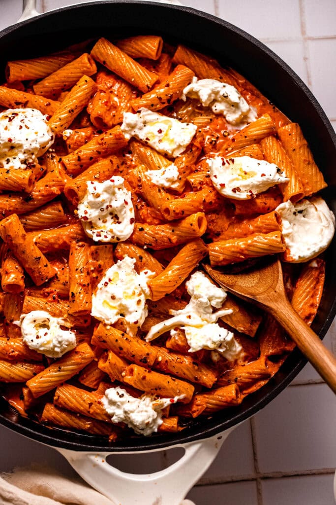 Overhead close up of Tomato pasta in skillet topped with dollops of burrata cheese.