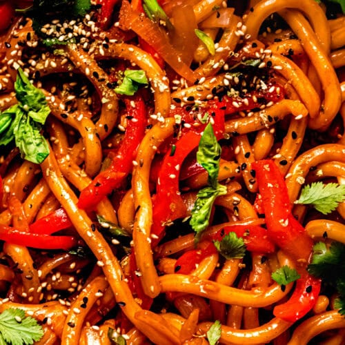 Spicy gochujang noodles served in a black bowl with chopsticks, photographed from above.