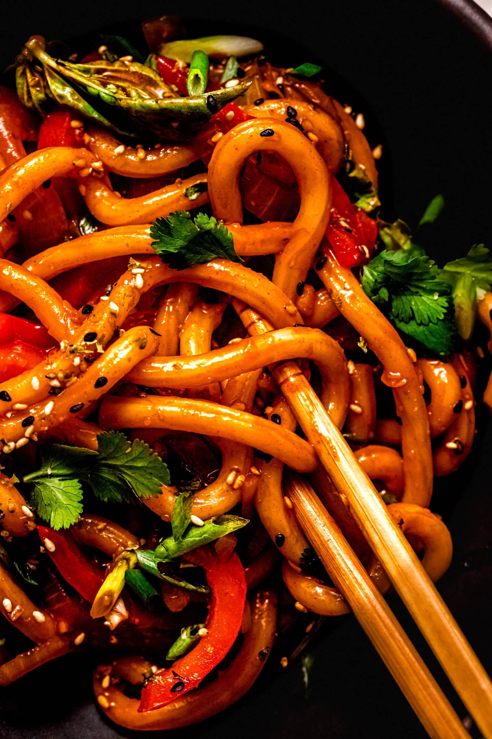 Overhead close up of gochujang noodles in black bowl with chopsticks.