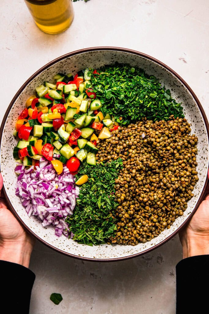 Lentil tabbouleh ingredients in large bowl before combining.
