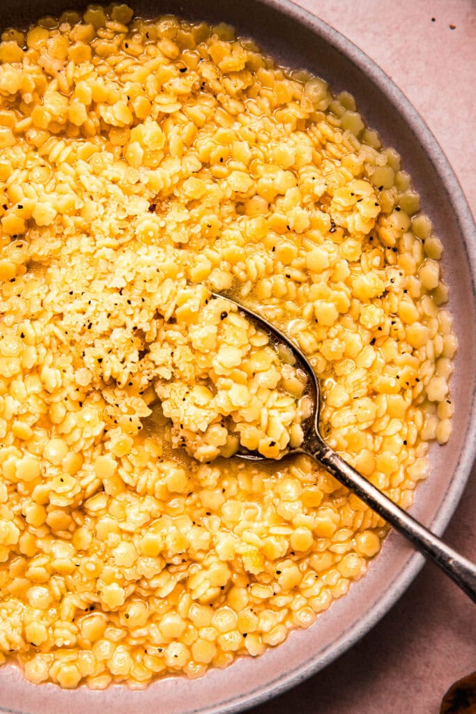 Overhead close up of spoon dipping into bowl of pastina.