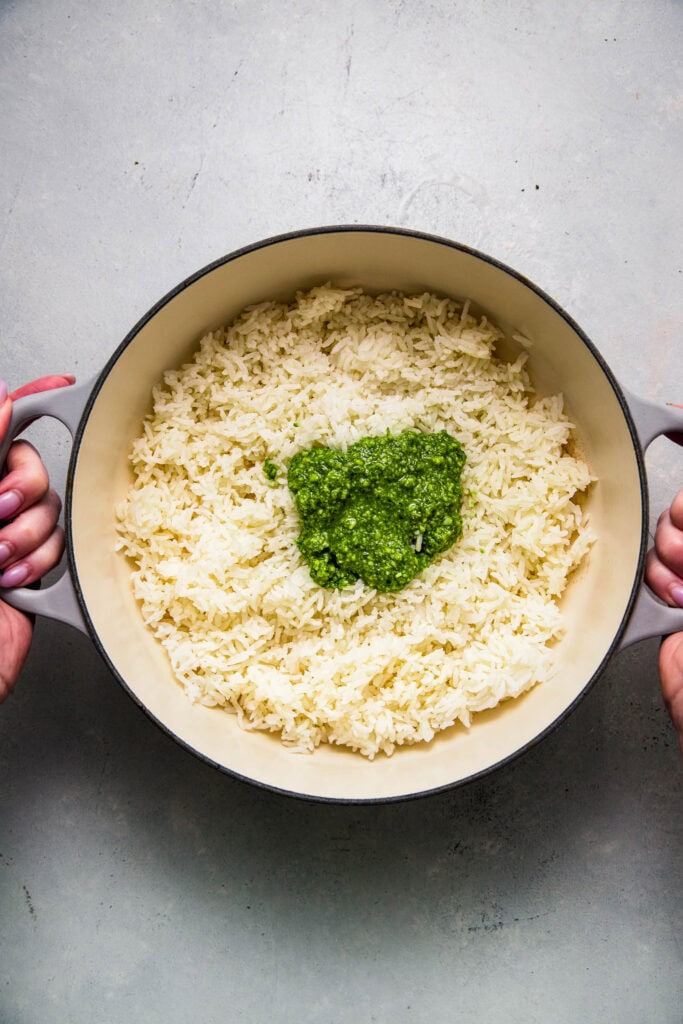 Cooked rice in pot with dollop of pesto.