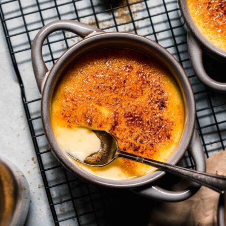 Creme brulee on cooling rack with spoon that's broken through the top.