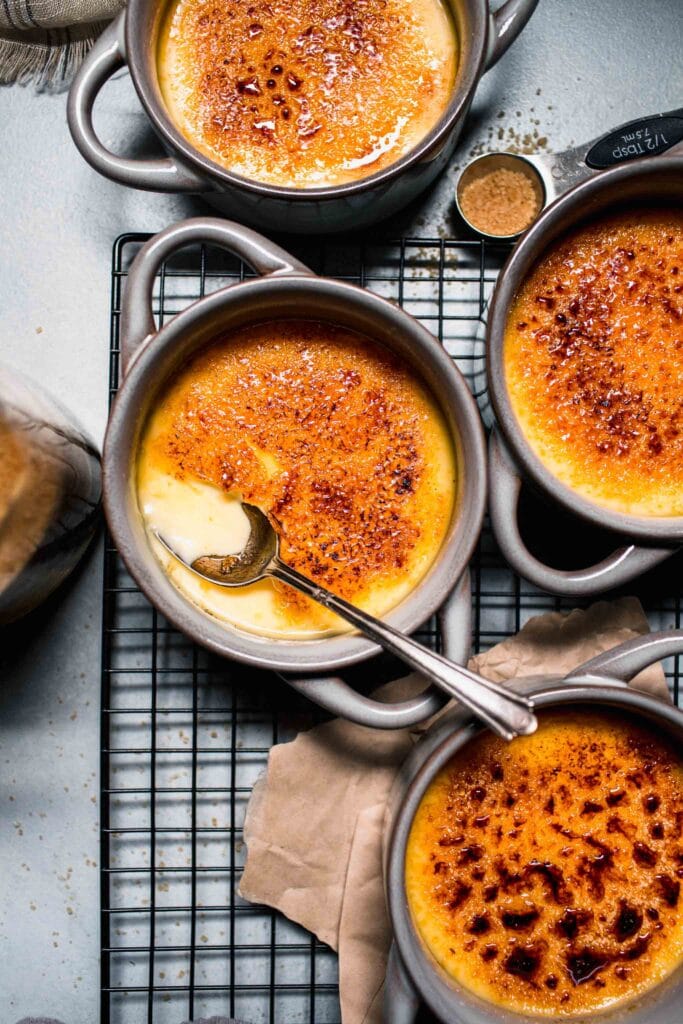 Crackly top of creme brulee broken with spoon. 