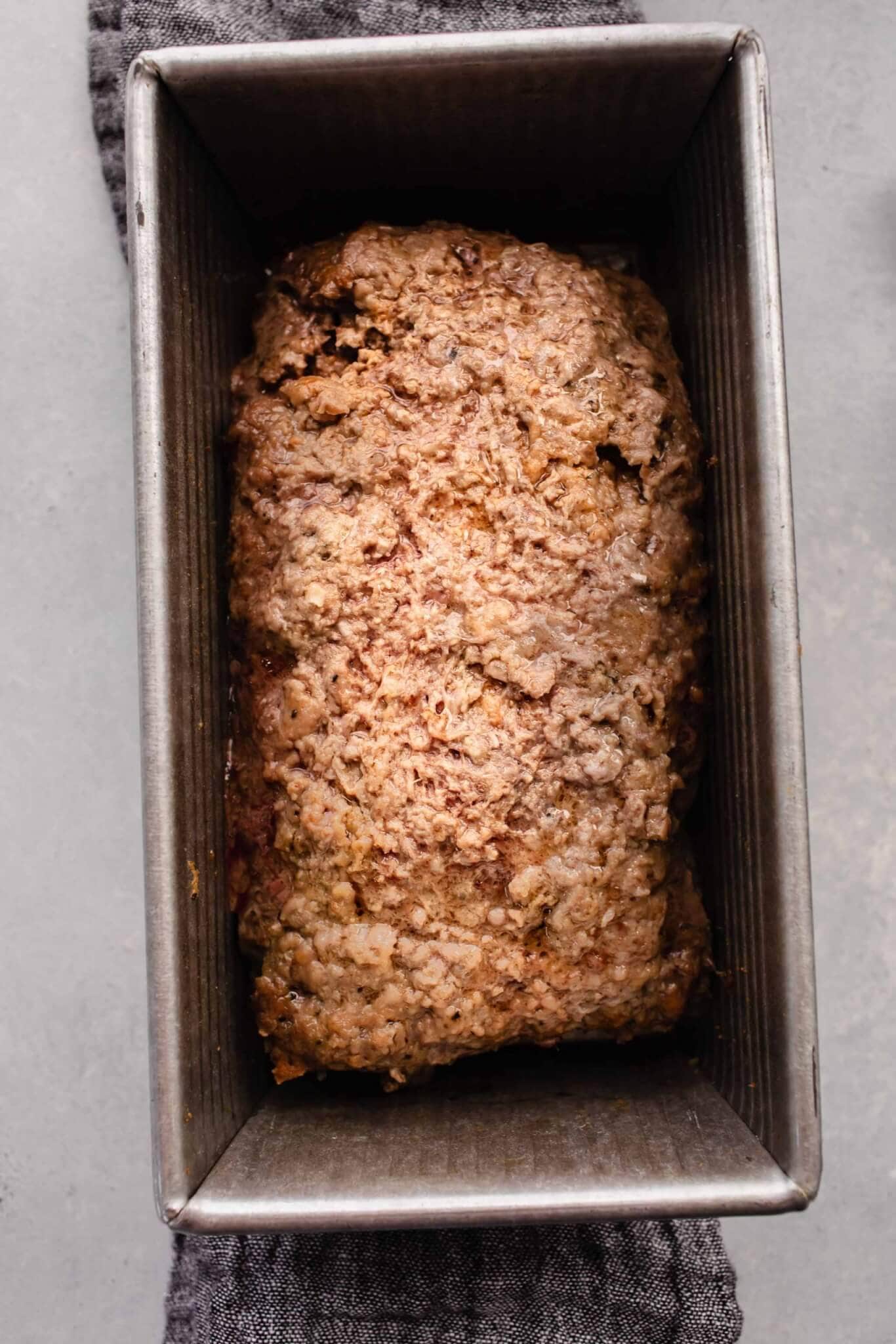 Half baked meatloaf in pan before slicing.