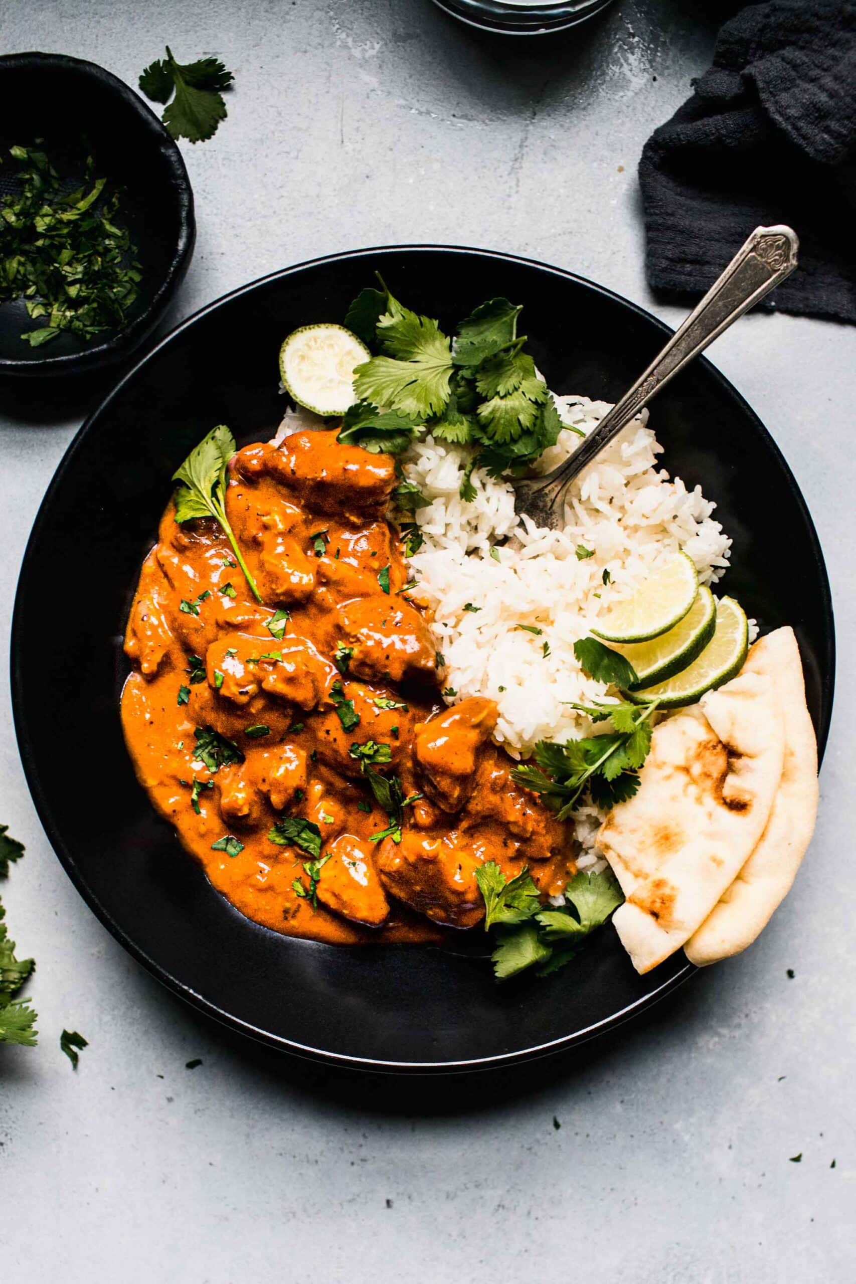 Overhead shot of slow cooker butter chicken in black bowl with rice.