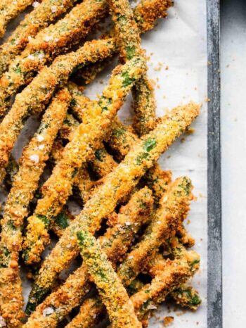 Close up of green bean fries on baking sheet lined with parchment.