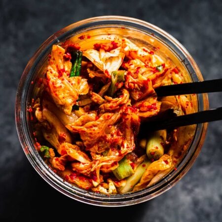 Overhead shot of kimchee in jar with chopsticks.