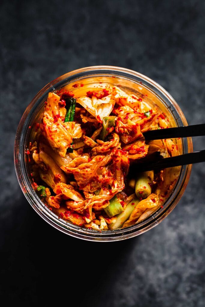 Overhead shot of kimchee in jar with chopsticks.