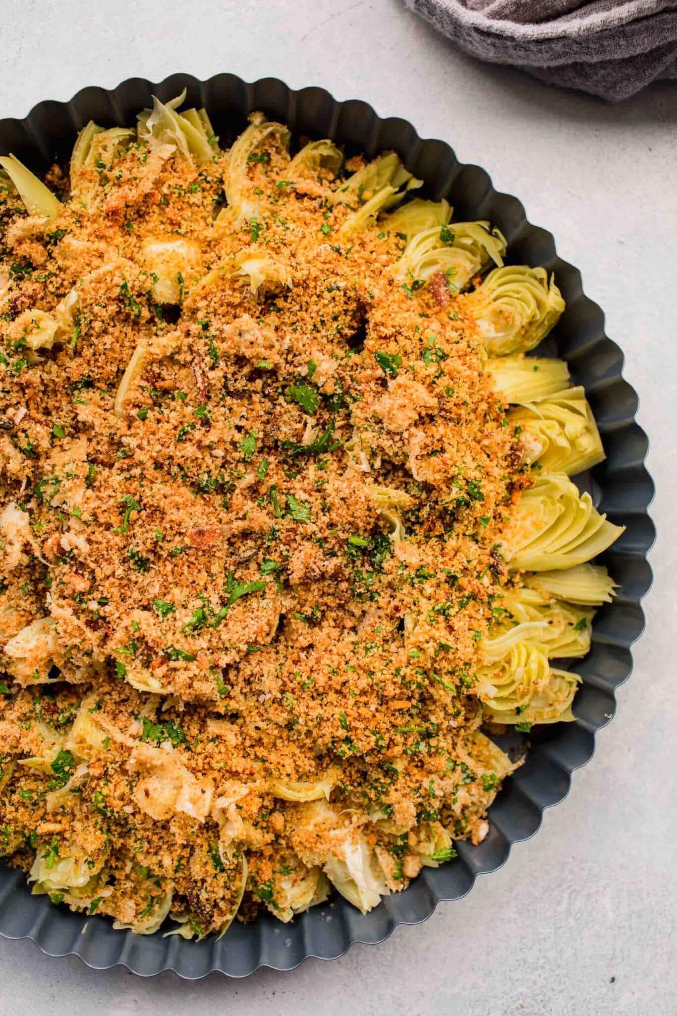 Artichoke hearts topped with breadcrumbs before baking.