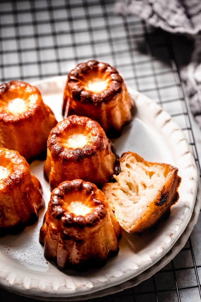 Caneles arranged on plate with one cut in half.