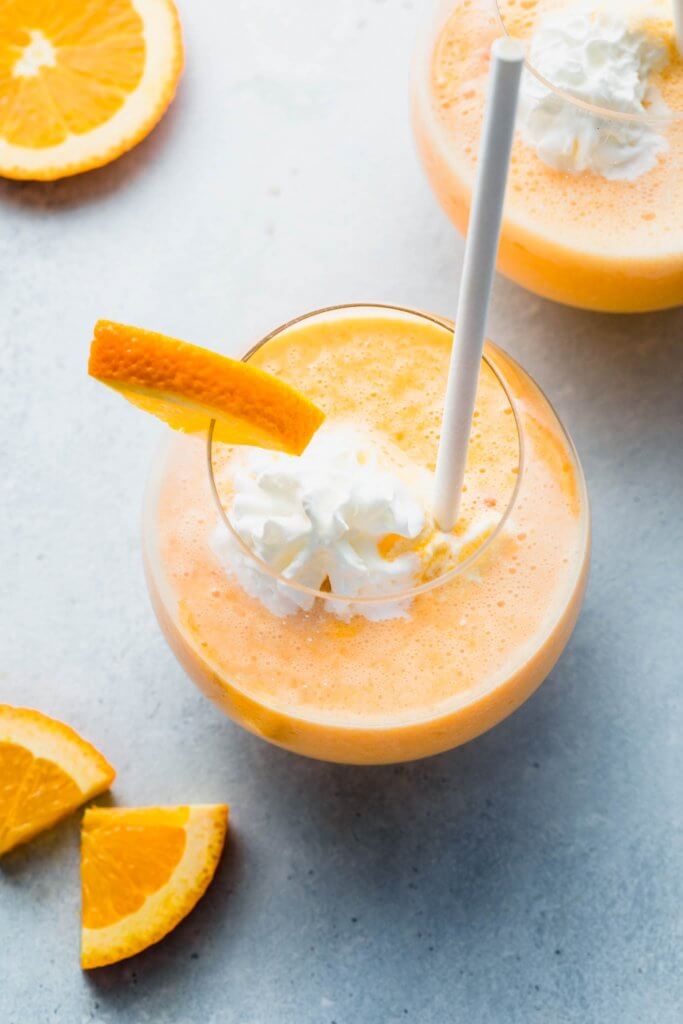 Orange julius topped with whipped cream and served with straw.